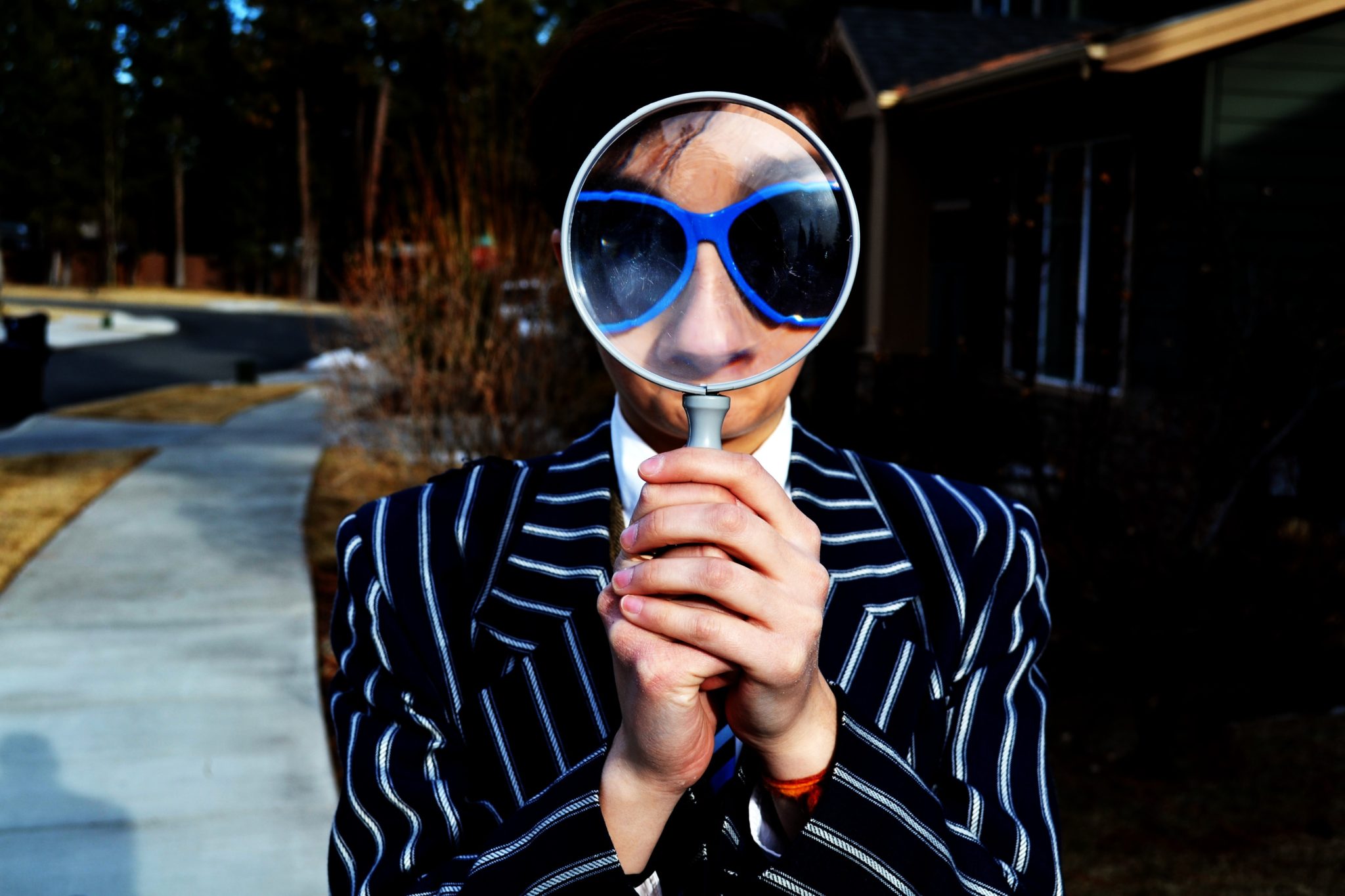 man in sunglasses looking through a magnifying glass