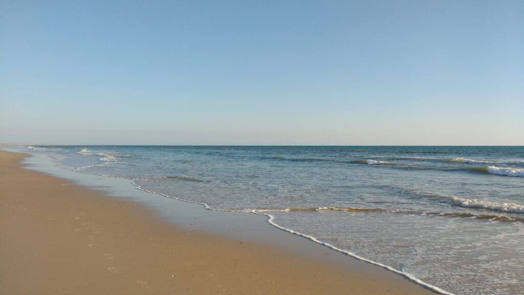 Photo of a beach. Matalascañas (Huelva - Spain).  Sand on the left, light, shallow surf on the right.