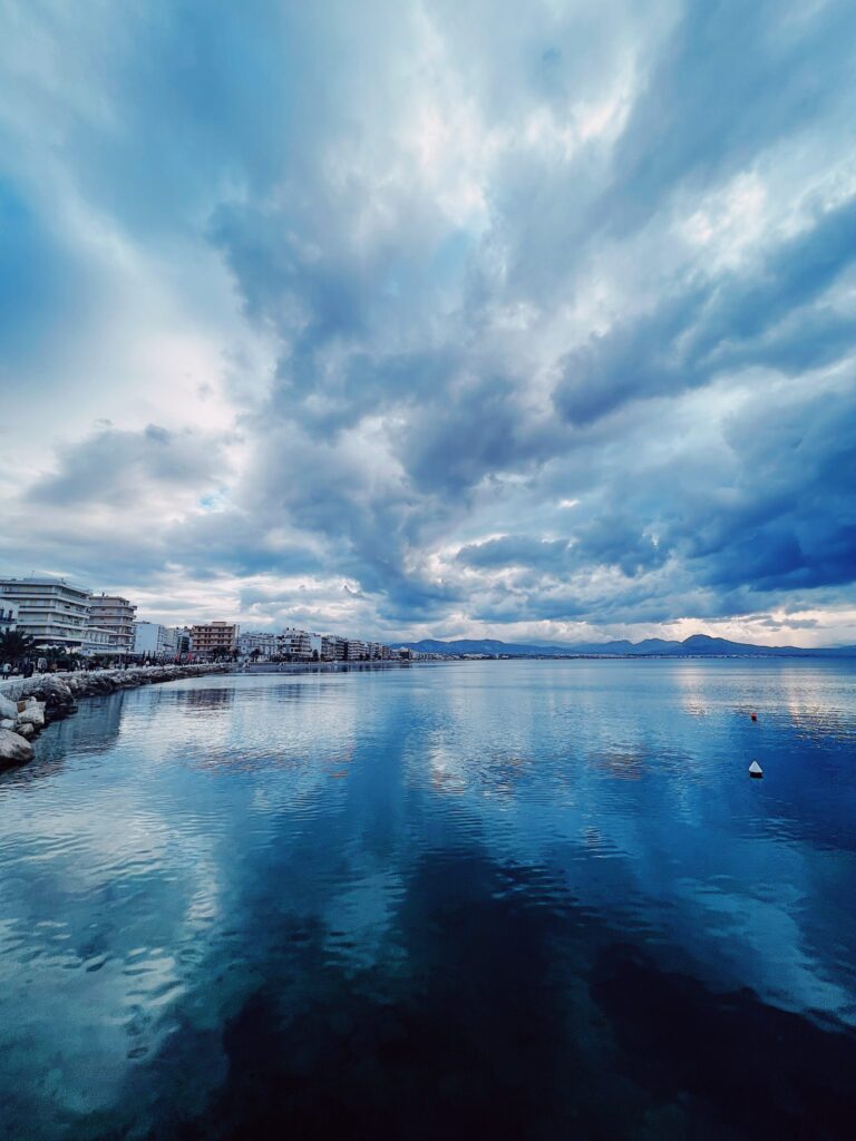 Looking across some water with a shoreline on the left curving toward center horizon. It's a cloudy day and there are hotels lining the entire beach.